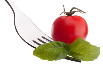 Basil leaf  and cherry tomato on fork isolated on white backgrou