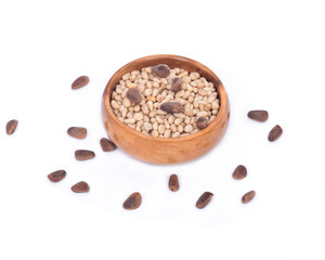 Organic pine nuts with and without shell in wooden bowl on white background