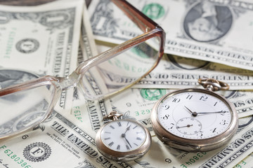 Time is money finance concept with old vintage clocks, dollar bills, spectacles