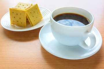 Black coffee and biscuits on wooden table