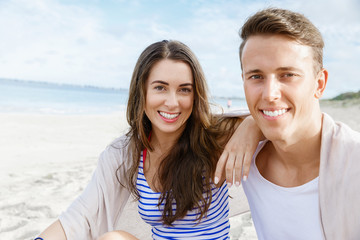 Obraz premium Romantic young couple sitting on the beach