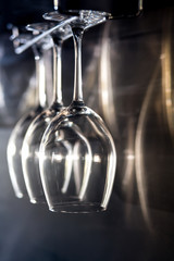 three wine glasses hanging on bar rack;