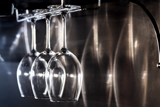 three wine glasses hanging on bar rack;