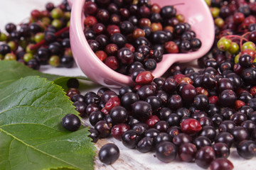 Fresh elderberry with leaf in glass dish on old wooden background