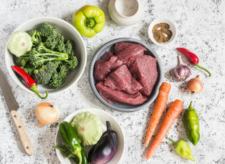 Raw ingredients for cooking lunch - beef meat and vegetables on a light background, top view