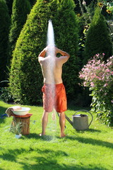 Mann unter Gartendusche, kühlt sich ab, wäscht sich