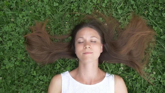 Carefree woman lying on grass and dreaming