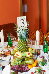 A wedding table with a vase of fruit. In the center of the pineapple, orange interior