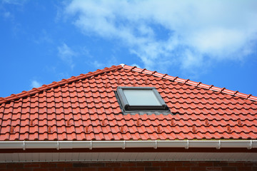Skylight on red ceramic tiles house roof with rain gutter. Skylights, Roof Windows and Sun Tunnels....