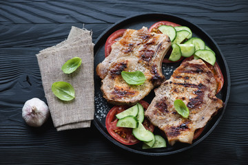 Frying pan with barbecued pork meat steaks on bone, top view