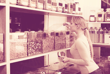 Young female customer selecting various nuts