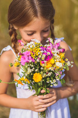 Cheerful kid smelling meadow bouquet