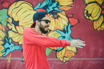 Young man  dances with a graffiti in the background