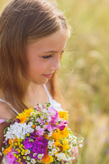 Dreamful child with flowers on field