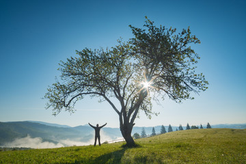 Man standing with raised hands on a hill
