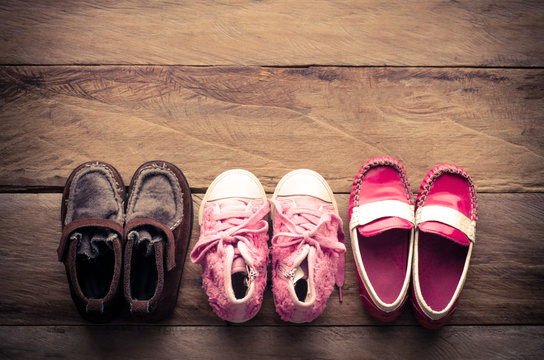 3 pair of baby shoes lined up on wood background