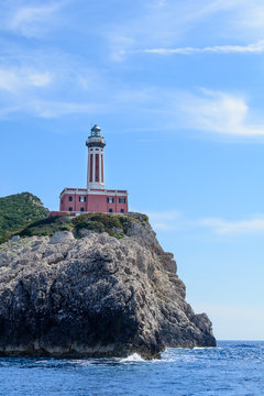 Lighthouse on a cliff in day time. Vertical image with red and w