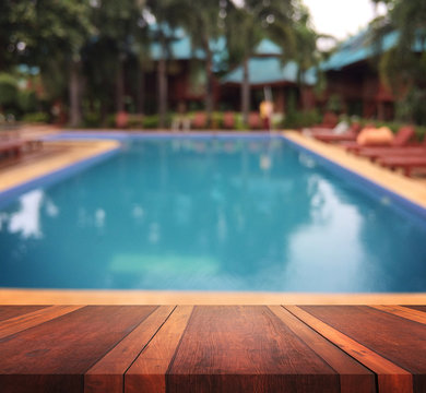 Empty brown wooden table surface and swimming pool blur background with bokeh image, for product display montage,can be used for montage or display your products