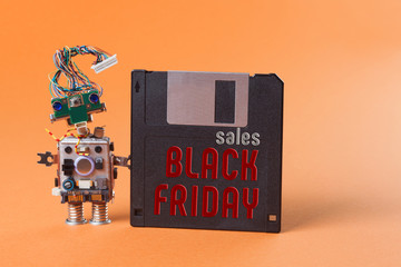 Black friday sales concept poster. Retro robot with floppy disk. Creative design character blue eyed head, electrical wire hairstyle. orange background