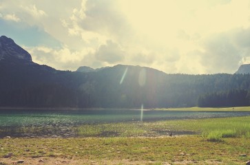 Idyllic lake landscape in the mountains on a sunny day; nature. Image filtered in faded, nostalgic, retro, Instagram style with intentional lens flare. Black lake, Durmitor, Montenegro. - 120386260