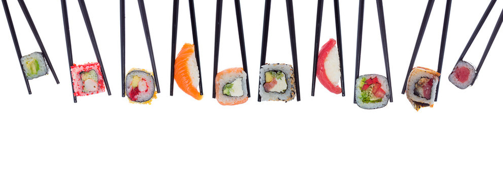 A lot of sushi and rolls in black chopsticks isolated on white background