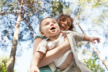 Fototapeta premium Baby boy with his motter in summer park. Love, family, care, tog