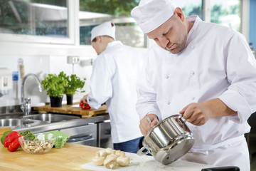 Professional chefs makes food dishes in large kitchen