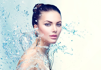 Beauty spa woman under splash of water over blue background