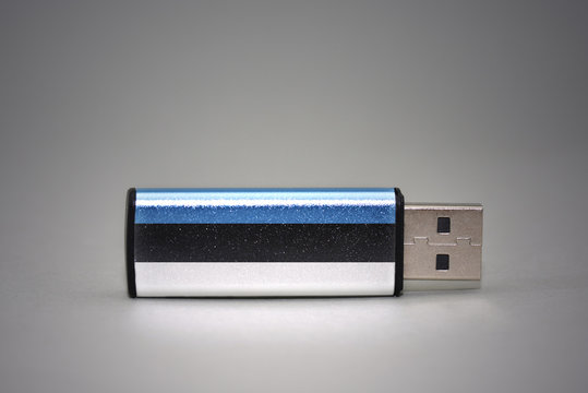 usb flash drive with the national flag of estonia on gray background.