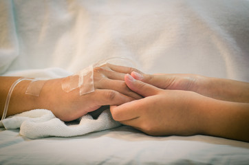 Child holding father's hand who fever patients have IV tube.