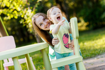 Fototapeta premium Mother with sitting on children's chair in park