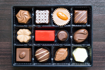 Different types of chocolate candies on a wooden background / Delicious chocolate candies in gift box on table close-up.