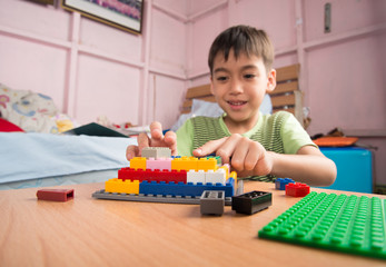 Little boy playing plastic block building indoor activity education