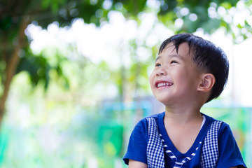 Happy asian boy looking up at park. Outdoors in the daytime