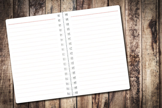 Open notebook paper page with red line on wood background for design with copy space for text or image.