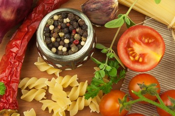 Raw pasta with tomatoes and parsley on a wooden background. Preparation diet food. The recipe for a simple dinner. Traditional pasta with vegetables.
