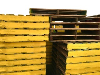 Mehrere Stapel gelber Holzpaletten für den Transport