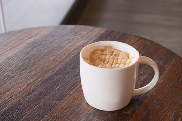 hot fresh coffee in white cup with silver spoon on wooden brown table at coffee time caramel