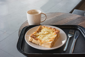 hot fresh coffee in white cup with silver spoon on wooden brown table and sandwich ham cheese plate silver fork and spoon at coffee time