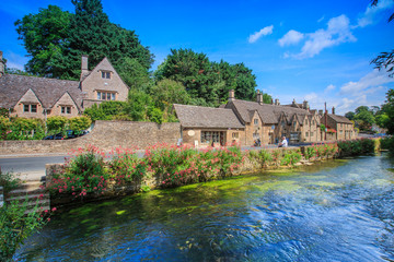 Fototapeta na wymiar BIBURY, ENGLAND, UK - JULY 9, 2014: Arlington Row traditional Cotswold stone cottages in Gloucestershire on JULY 9, 2014, England. Bibury it the most depicted village in the world.