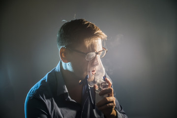 the young man keeps an inhaler to treat a cough on a dark background closeup