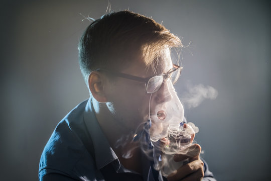 the young man keeps an inhaler to treat a cough on a dark background closeup