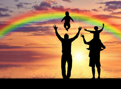 Pair of gay men and their children playing at sunset