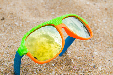 Colorful children sunglasses on the beach