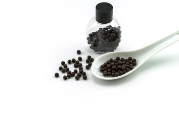 Fototapeta na wymiar Black pills of traditional medicine or Black bolus near bottle and white ceramic spoon on white background.