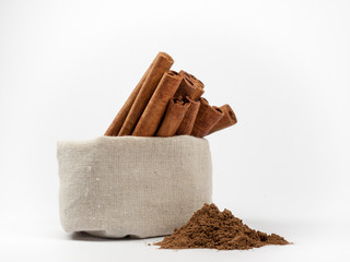 Bunch of cinnamon in canvas bag and cinnamon powder isolated on white background