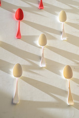 White and red spoons ona white wall, with pattern shadows