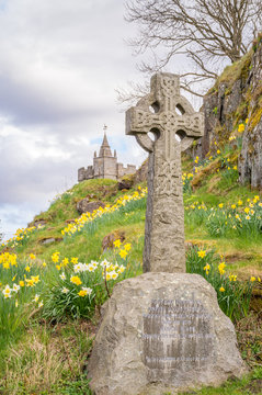 Old stone celtic crosses on a graveyard, with daffodils and Sterling castle in the background