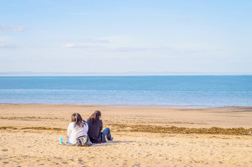 A black couple (afro-american) sitting on the sand beach by the sea or ocean