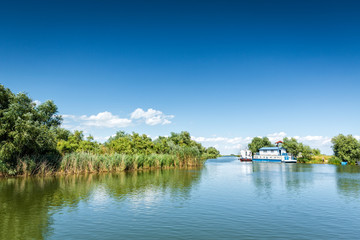 Fototapeta premium Typical Danube Delta landscape with lakes, canals and lush vegetation on a clear sunny day, in Gura Portitei resort, Romania